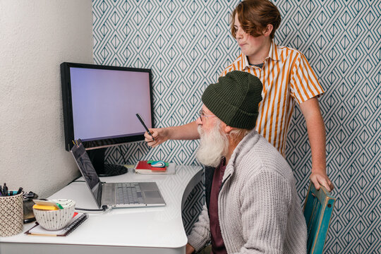Grandson helping his grandfather to use the computer