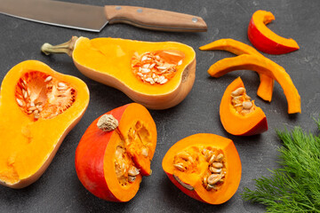 Sliced orange pumpkin and knife on black.