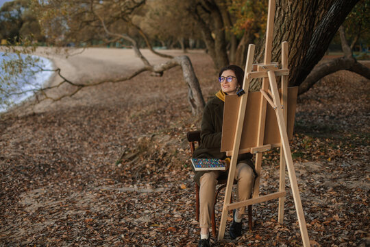 the painter paints in autumn by the lake 