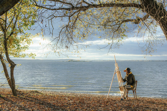 the paintress paints on the shore on an autumn evening