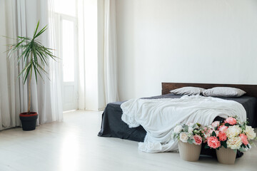 interior of a white bedroom with bed and flowers with window