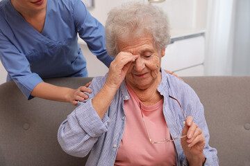 Nurse taking care of senior woman with headache indoors - obrazy, fototapety, plakaty