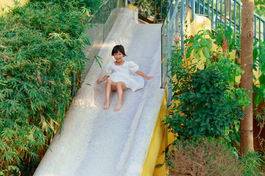 Asian little girl playing slide outdoors