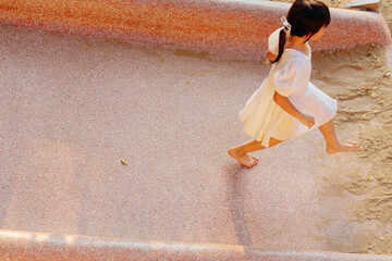 Asian little girl playing slide outdoors