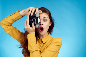 pretty woman photographer with camera in yellow shirt on blue background - obrazy, fototapety, plakaty