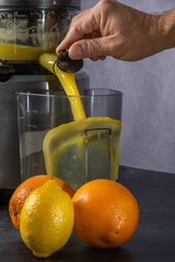 produce juice from oranges and lemons with a juice extractor. everything is photographed on a grey background