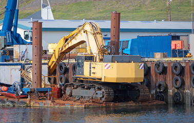 Empty yellow excavator in a small harbour