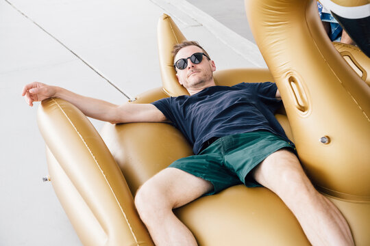 Handsome man wearing sunglasses lying on swimming float in patio