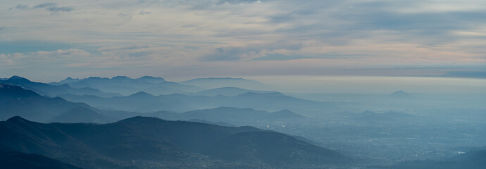 Amazing drone aerial landscape at the Italian Alps in winter and autumn. Morning panorama. Fall sunrise at the alps with moisture and pollution in the air. Silhouette of the mountains and hills