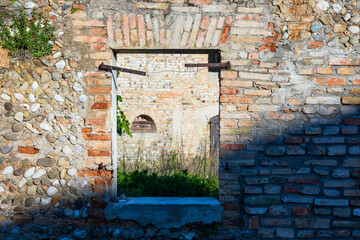 Vecchia finestra aperta su cortile di vecchio edificio abbandonato e in rovina. Facciata di abitazione costruita con pietre e mattoni.