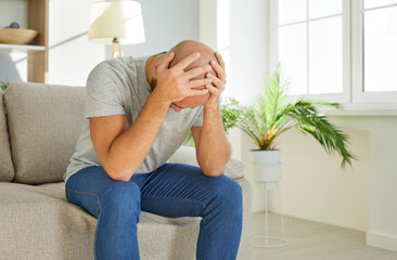 Sick young man hold head in hands struggle with headache or migraine at home. Unhealthy ill male...