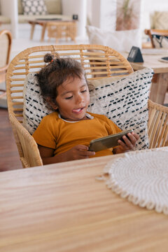 Child sticking tongue out while watching cell phone 