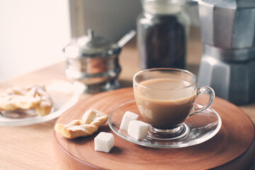 Still-life in the kitchen during breakfast with coffee pot, sugar bowl, sugar cubes, fresh homemade cakes and cup of latte. Good morning and Tasty Breakfast concept. Table Setting theme.