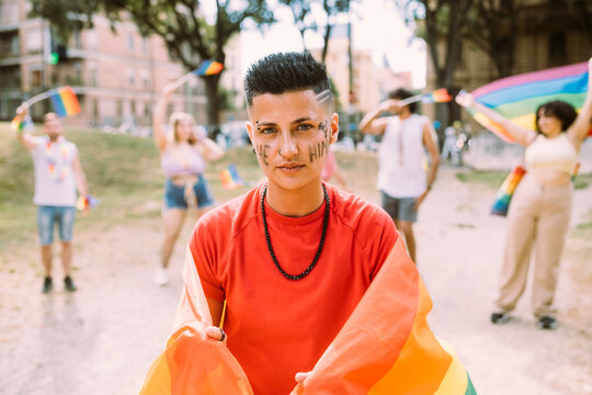 Young woman with rainbow flag protesting for equal rights in pride event