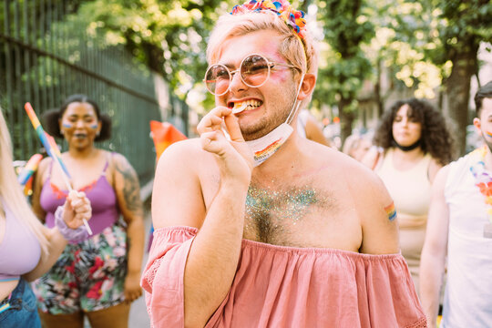 Smiling gay man eating in pride event during pandemic