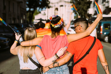 Multi-ethnic female friends walking on street during pride event