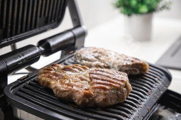 Hot steak on the electric grill at home in the kitchen
