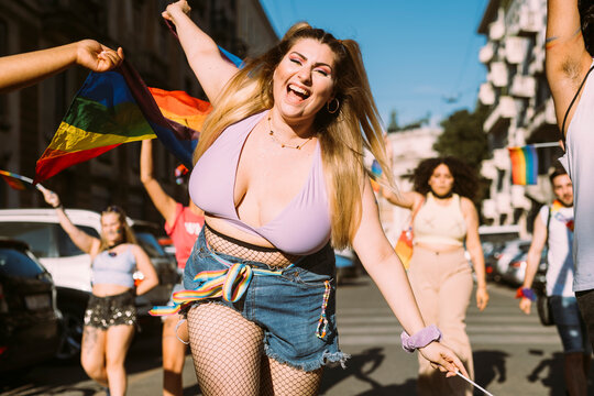 Cheerful woman with male and female friends protesting in pride event on sunny day