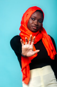 Young woman showing stop gesture in front of blue background