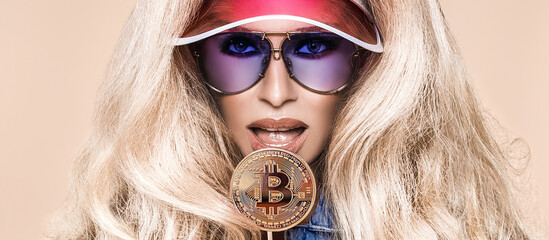 Beautiful blonde girl with bitcoin lollipop and sunglasses. Bitcoin cryptocurrency. Sexy woman with...