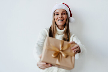 Beautiful woman in Santa hat posing with gift box on white background
