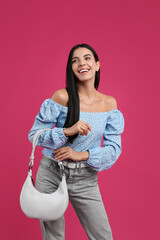 Fashionable young woman with stylish bag on pink background