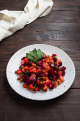 Vinaigrette with beetroot and boiled vegetables, traditional Russian homemade salad. Dark wooden background, copy space.