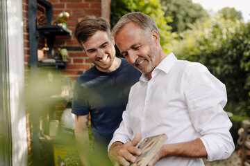 Father showing mosaic tile to son while standing outdoors
