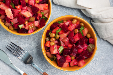 Vinaigrette with beetroot and boiled vegetables, traditional Russian homemade salad. Serving bowls with a cold snack on the table, copy space.