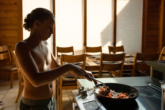 Silhouetted boy fries bacon