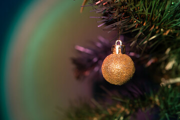 Artificial Christmas tree with gold decoration. Blurry, colorful background. 