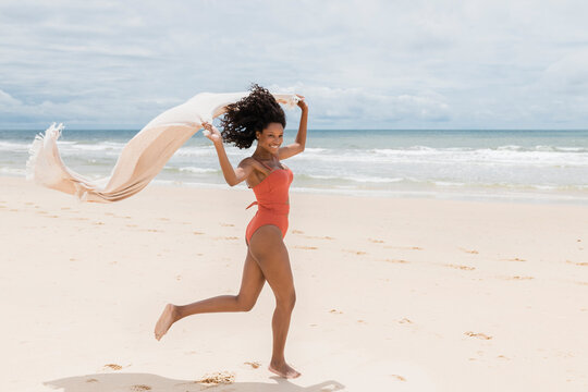 Smiling woman running with towel at beach