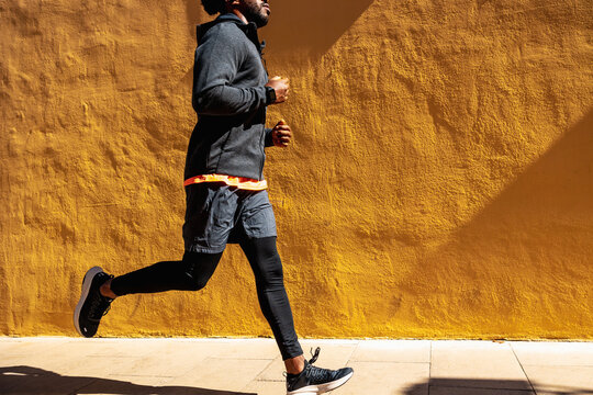 Crop black man running on street