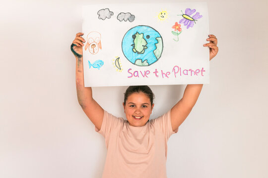 Smiling girl holding poster of environmental issues at home