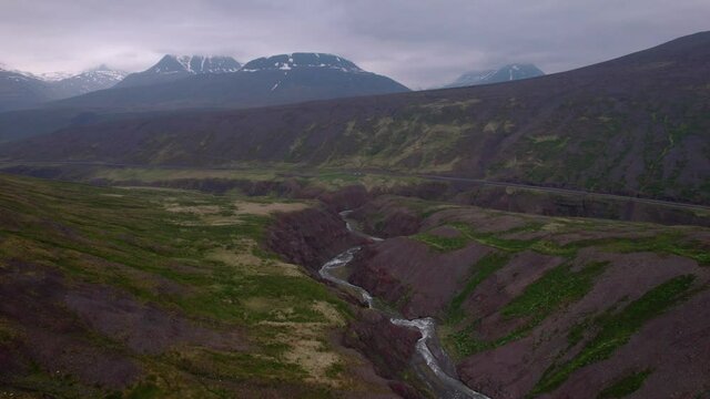 Aerial flying over interesting Icelandic landscape with road in the distance. Dark overcast day.