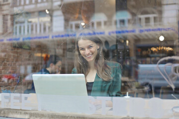 young woman photographed through the glass of a bar window