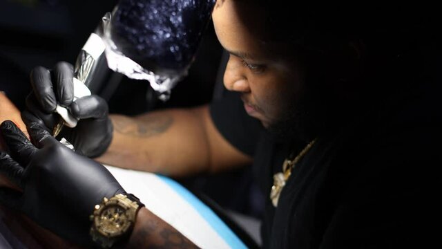 Portrait of tattoo master busy with his work at tattoo shop. Close up.