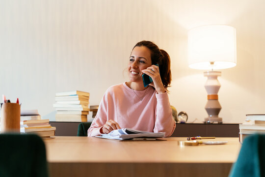 Smiling Hispanic professor talking on smartphone