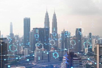 Technology hologram over panorama city view of Kuala Lumpur. KL is the largest tech hub in Malaysia, Asia. The concept of developing coding and high-tech science. Double exposure.
