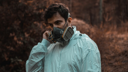 Man in white overalls wearing a gas mask in a post apocalyptic nature
