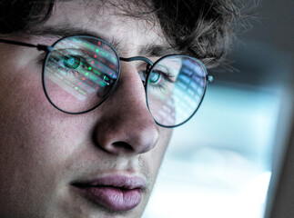 Teenage boy with eyeglasses checking stock data online at home