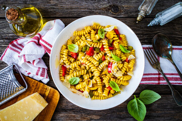 Pasta with vegetables and basil on wooden table
