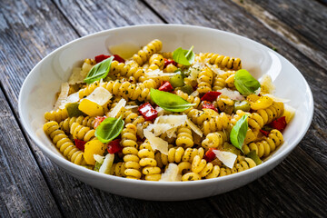 Pasta with vegetables and basil on wooden table
