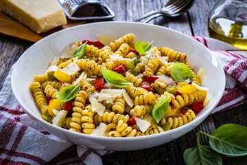 Pasta with vegetables and basil on wooden table
