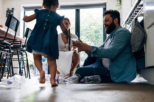 Daughter helping parents collecting crushed plastic bottle at home