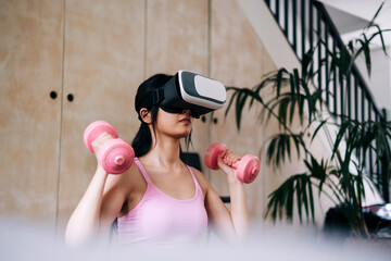 Young woman using virtual reality headset while exercising with dumbbells at home