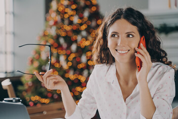 Young happy european businesswoman speaking on mobile phone with customer during winter holidays