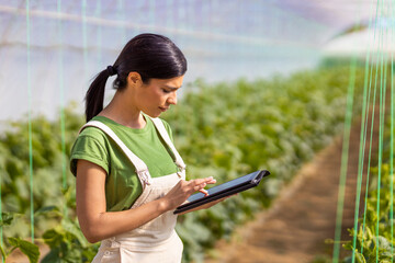 Female farmer using digital tablet in greenhouse