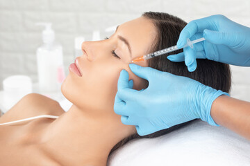Cosmetologist makes rejuvenating anti wrinkle injections on the face of a beautiful woman. Female...