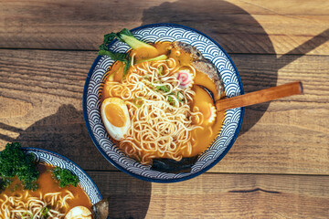 Asian noodle soup, ramen with vegetables and edd in a bowl on a table at asian restaurant.